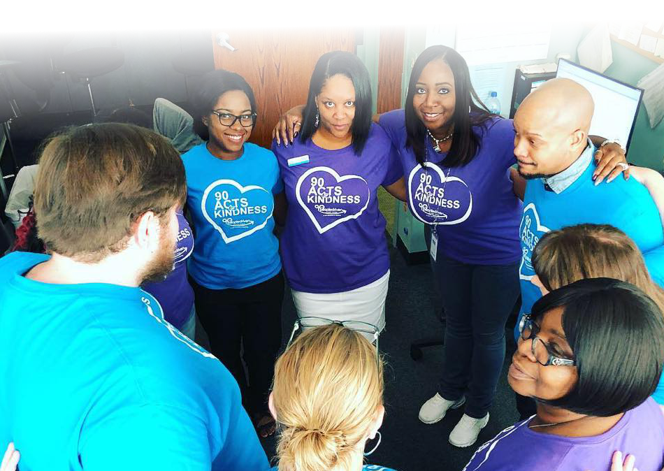 our southfield team huddles in a circle with their arms around each other wearing their "90 acts of kindness" tshirts Our 90 Acts of Kindness Goal