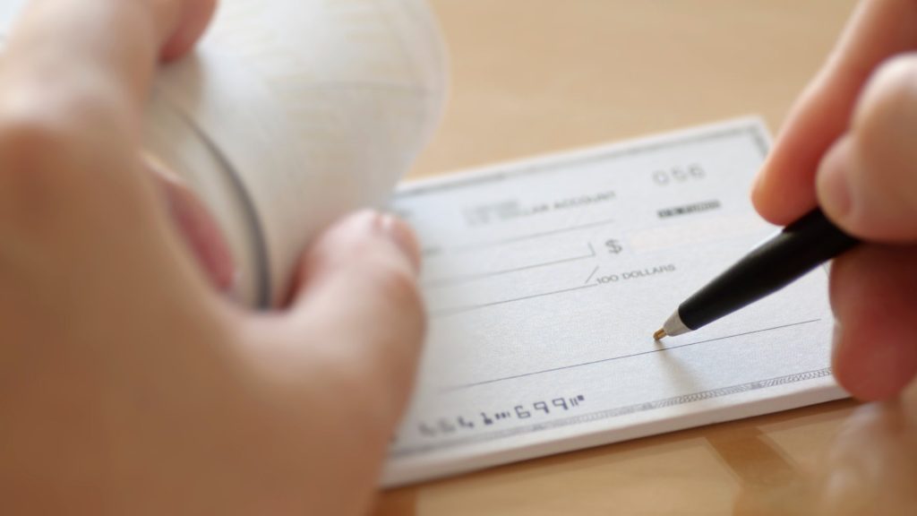 A person signing their name on a check.