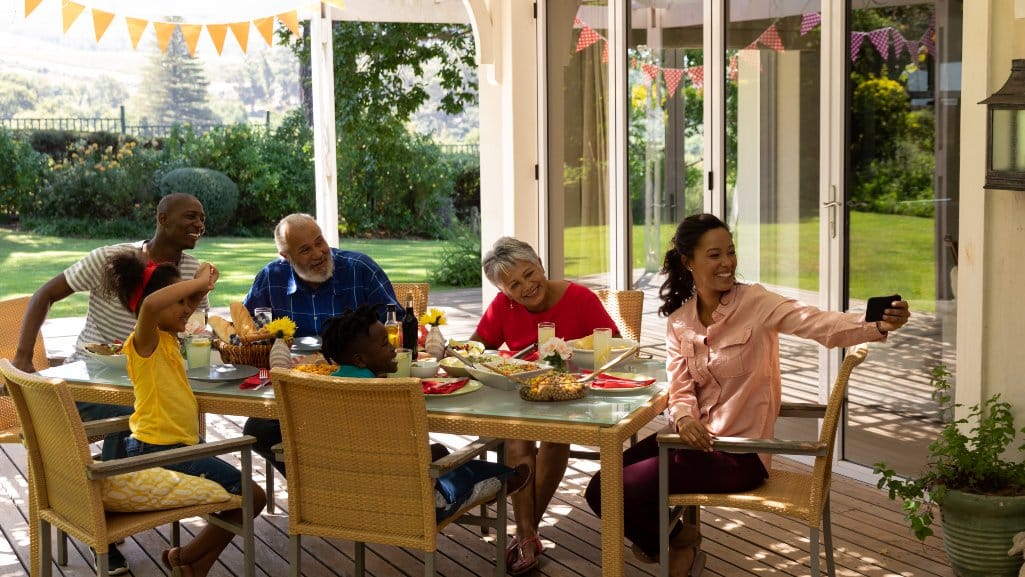 Family enjoying a meal at a table on their back porch financed by a home equity loan.