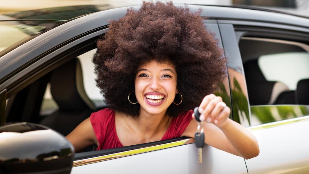 Smiling woman, showing her car keys while sitting in her new car financed with an Auto Loan from People Driven Credit Union.