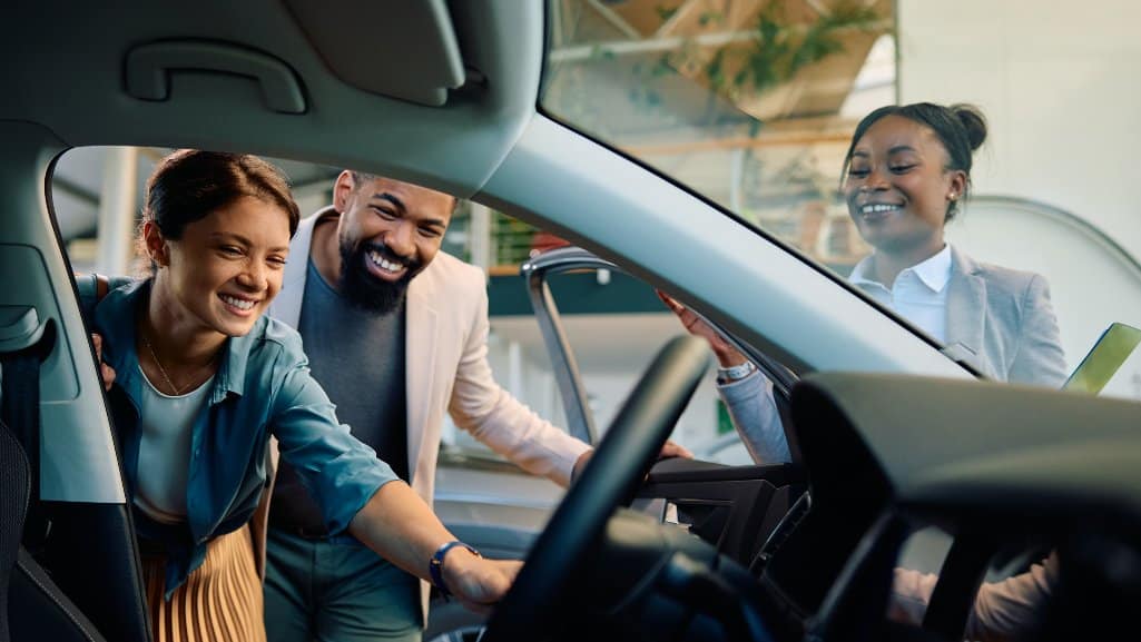 Couple inspecting a car while shopping at an auto dealership.