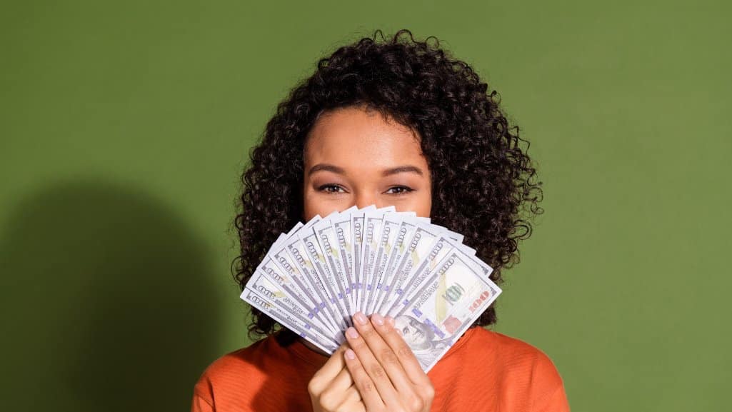 Woman holding a slew of hundred dollar bills she got with a personal loan from People Driven Credit Union.