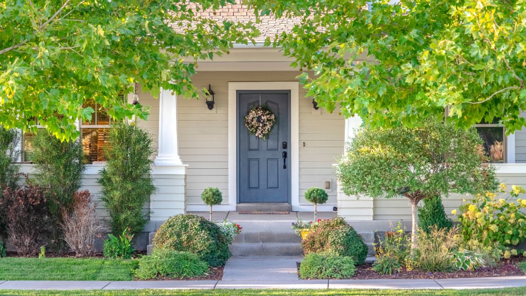 Front door of a home surrounded by leafy trees.