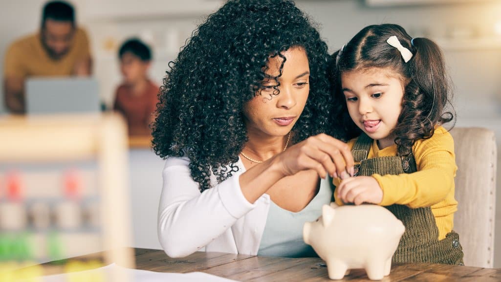 Mother helping her young daughter save coins for her big dreams.