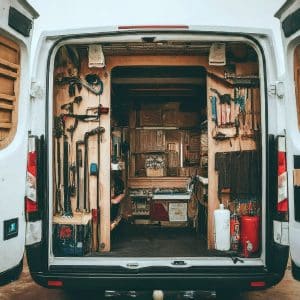 Work truck parked with it's rear doors open, showing tools neatly racked inside.