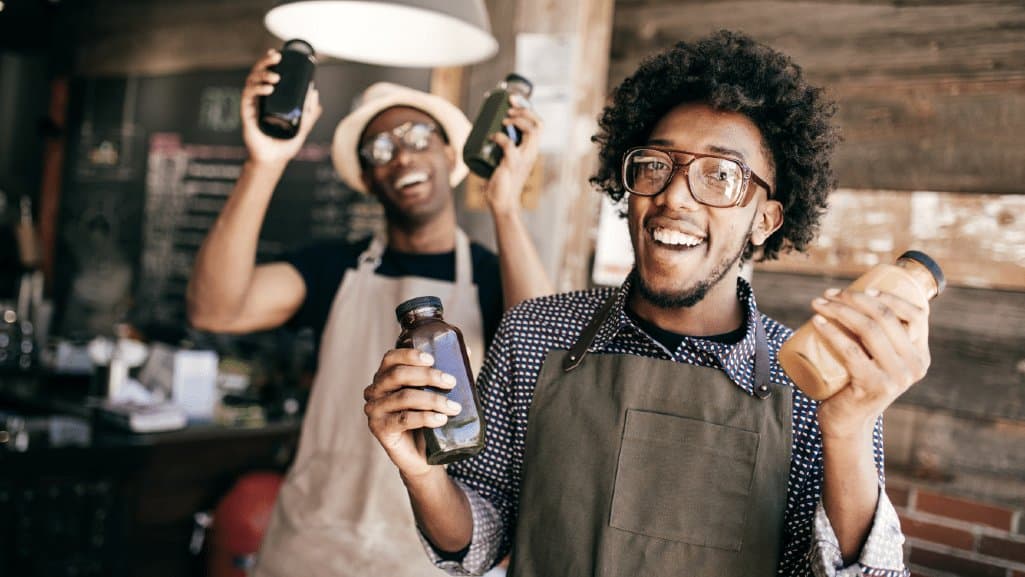 Two Michigan small business owners hold up their products for the camera.