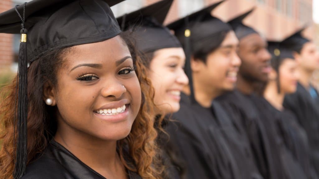 College graduates in cap an gown lined up to receive their diplomas.