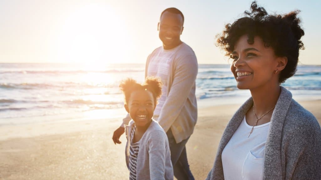 Family walking on the beach, enjoying their summer vacation.