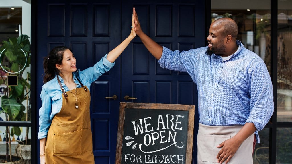 Two business owners high fiving each other after getting approved for a business loan from PDCU.