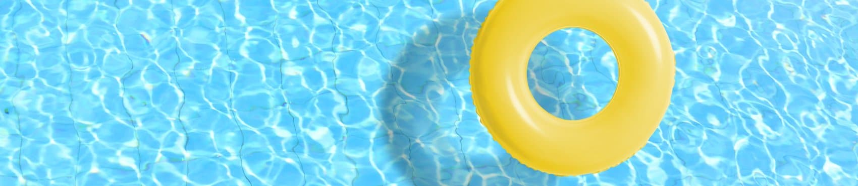 Yellow swimming pool ring floating in blue pool water.