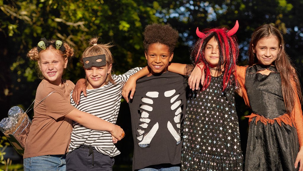 Group of children wearing fun DIY Halloween costumes outdoors, celebrating budget-friendly Halloween fun with People Driven Credit Union.