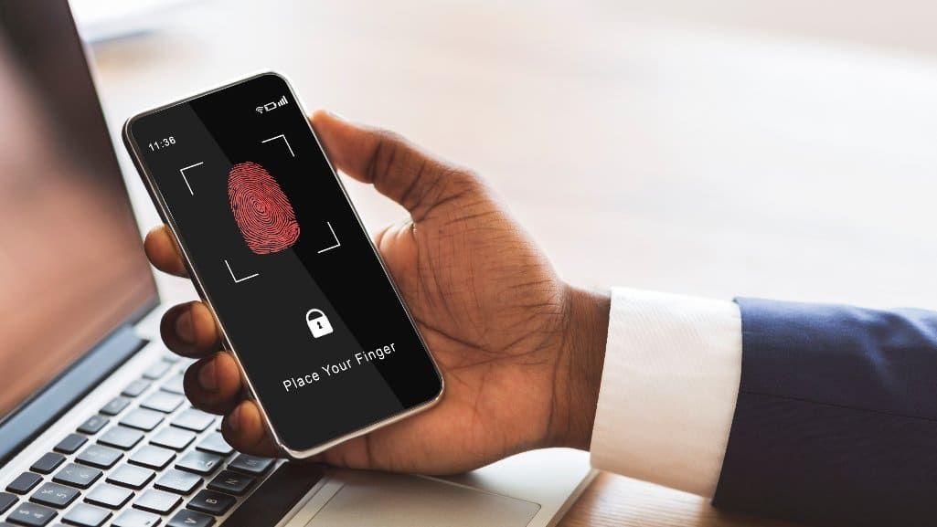 Person holding a smartphone displaying a fingerprint login screen, symbolizing secure digital access and cybersecurity awareness.
