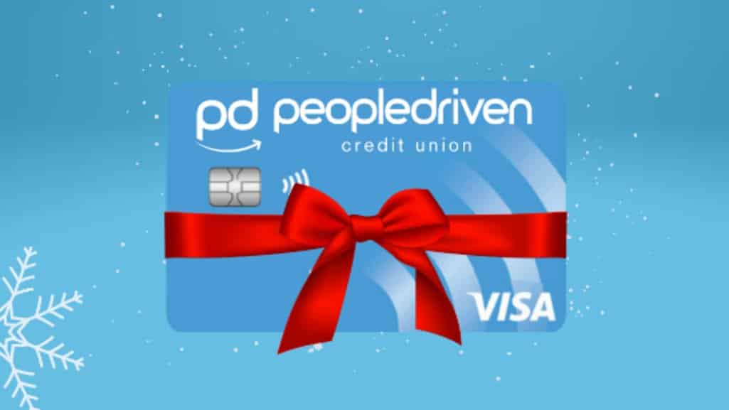 People Driven Credit Union Visa credit card wrapped with a red bow on a winter blue background with snowflakes, representing the Stretch Your Holiday Dollars campaign.