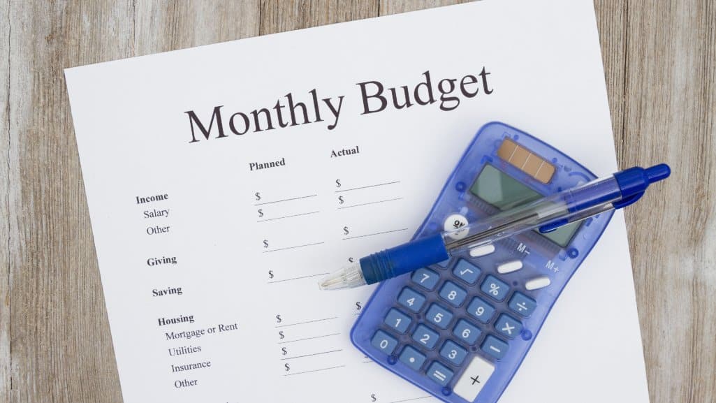 Monthly Budget worksheet with a calculator and pen.