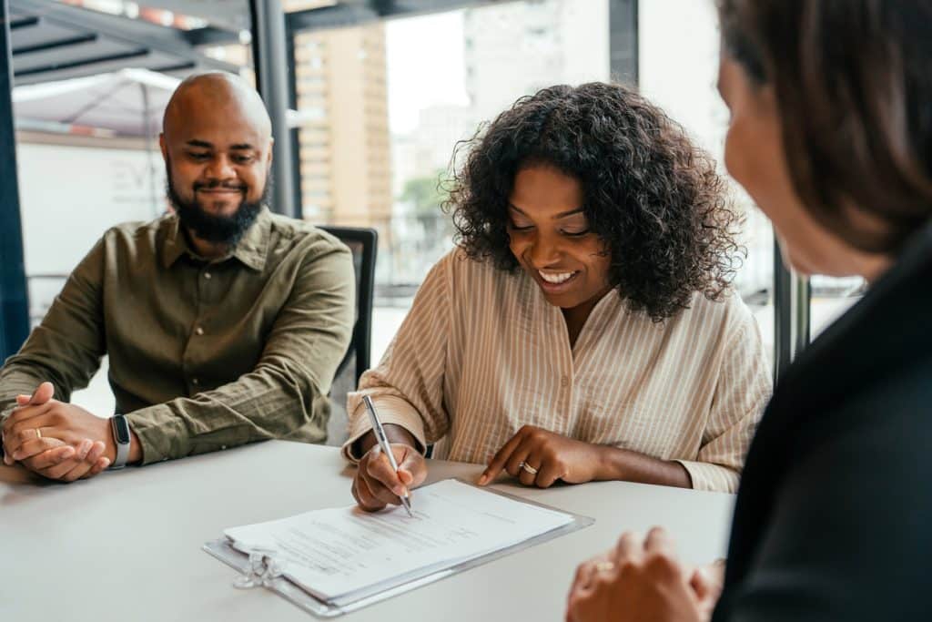 Couple Signing Paper While Closing on a House
