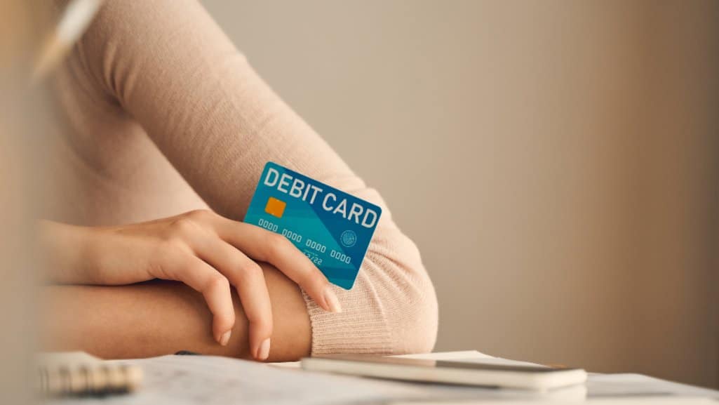 Close up of a debit card with overdraft protection, in a woman's hand.