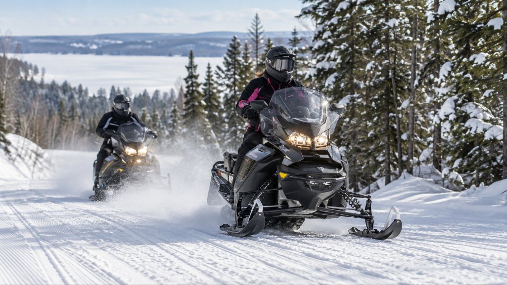 Snowmobiles riding up a hill whose monthly payments can be compared by using a snowmobile loan calculator.